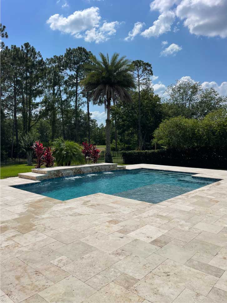 A clean swimming pool with blue water in a beautiful back yard.